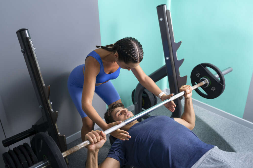 high-angle-woman-helping-fit-man-gym